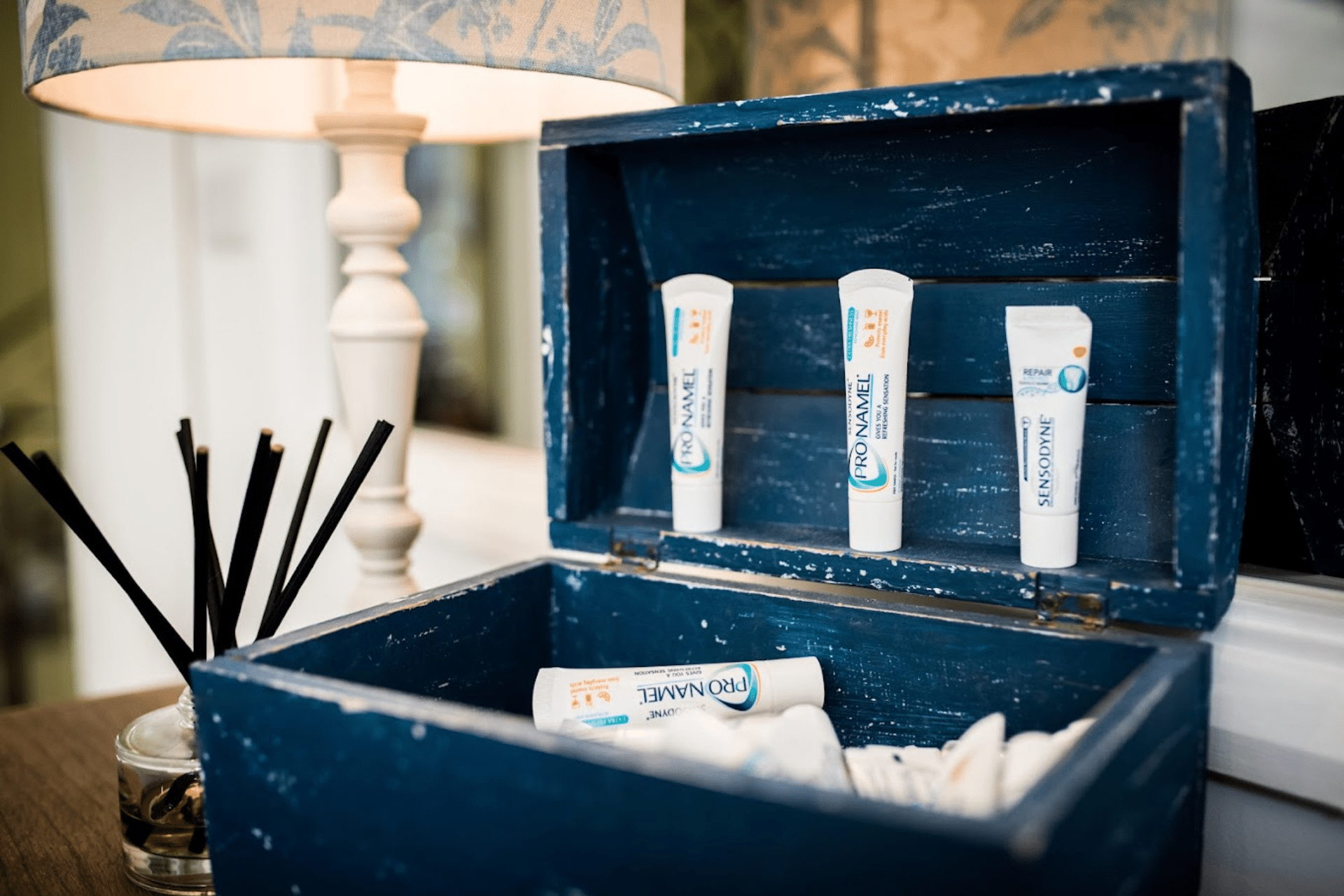Hygienist - Hampshire Dentists Pain Free Dentist in Southampton A blue wooden box filled with toothbrushes and toothpaste, representing essential items for daily oral care routines being discussed at Hampshire Dentists